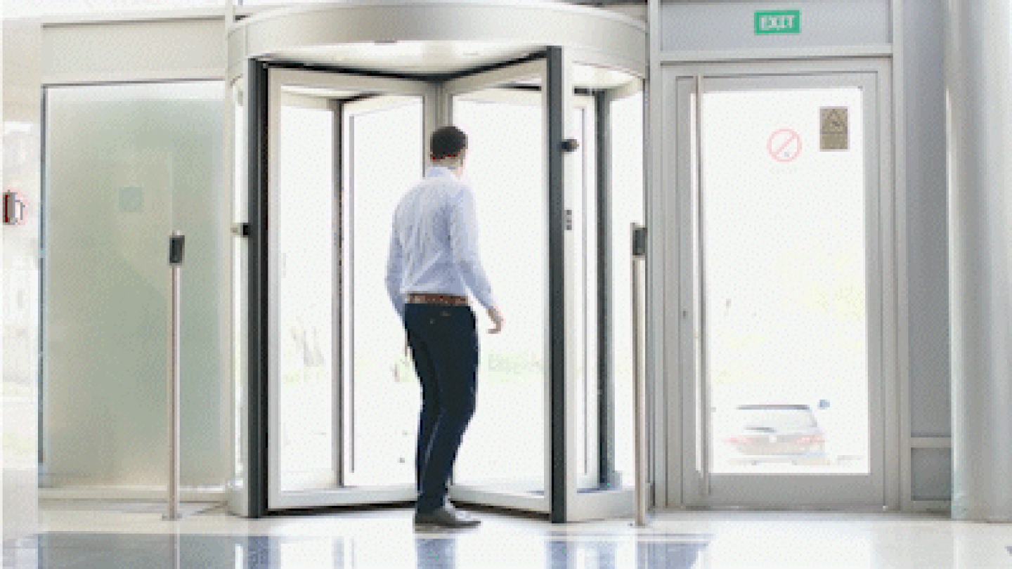 Person struggling to walk through a revolving door