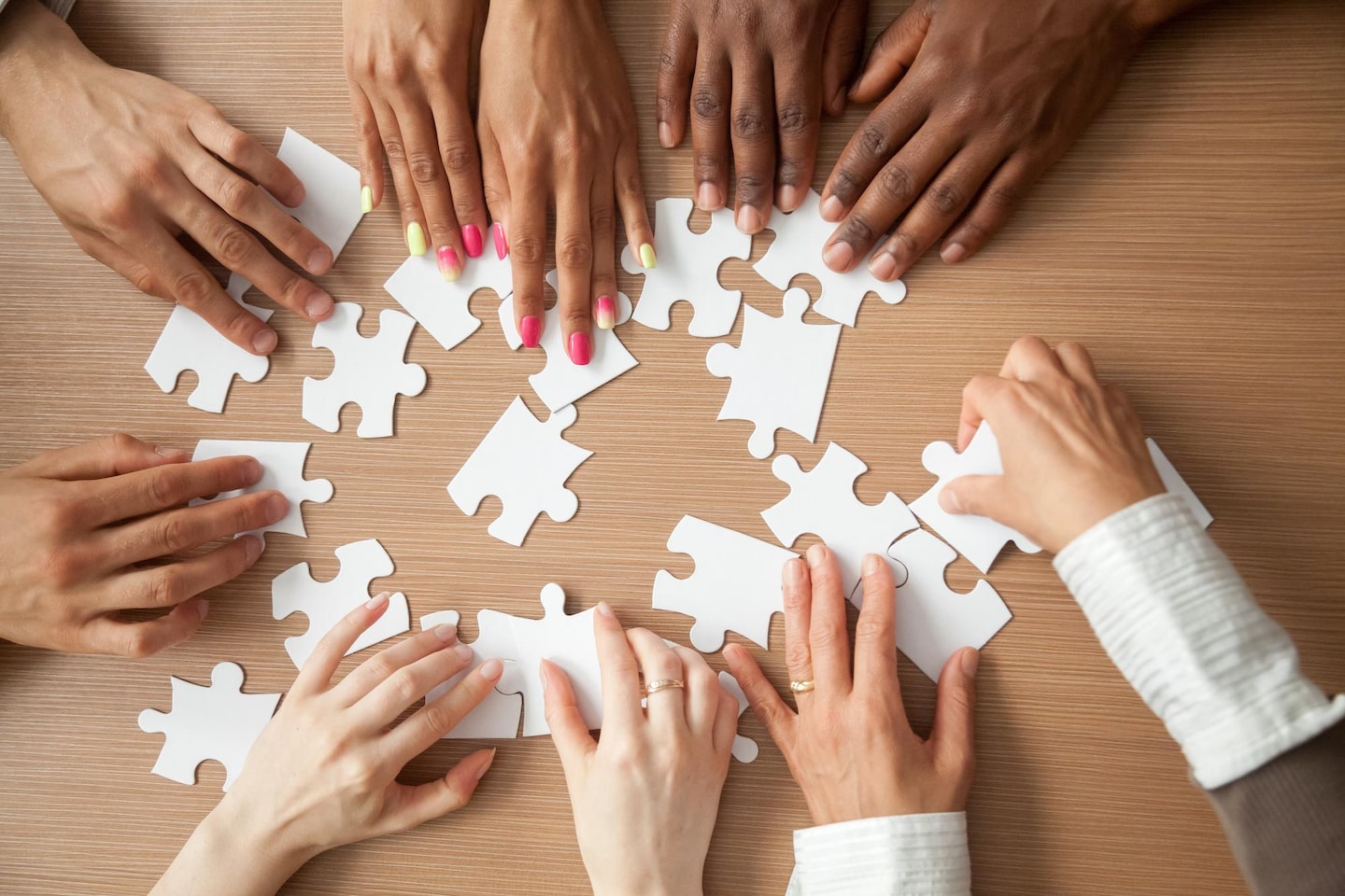 close up of a group of hands putting together a puzzle